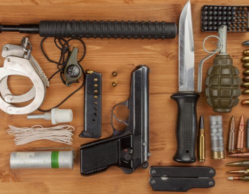 A wooden table displaying a variety of weapons and ammunition.